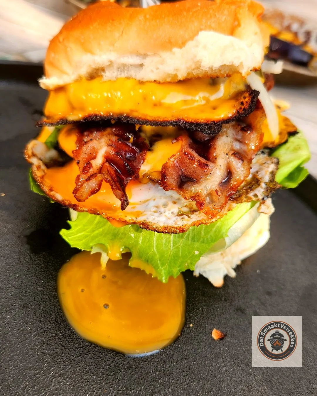 Smashburger met spek, gesmolten cheddar, spiegelei en sla op een briochebol